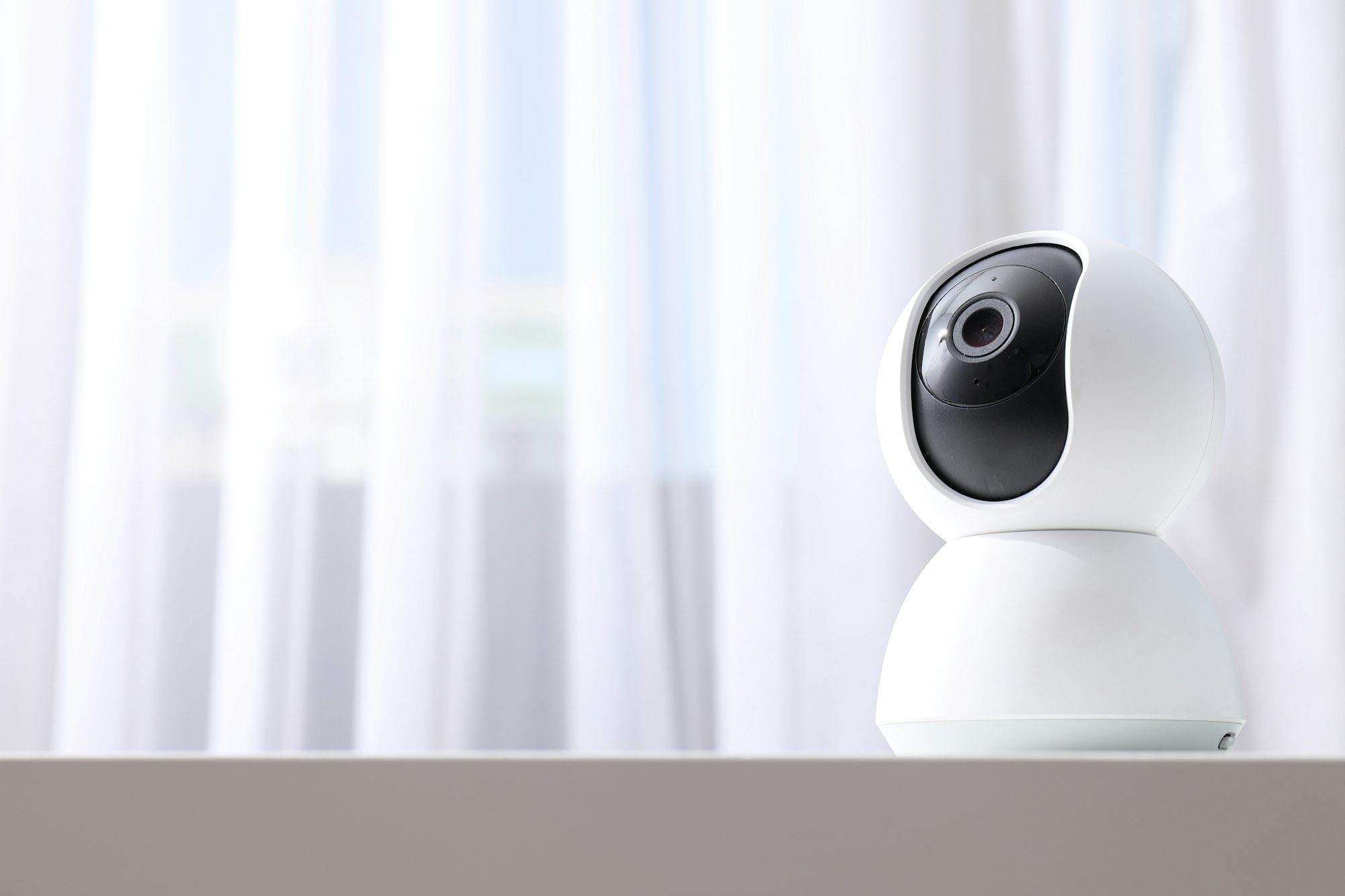 Home security camera on light background, space for text